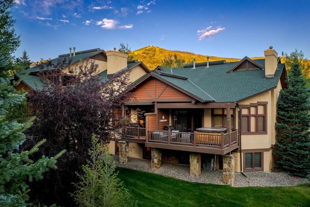 2755 Waterstone Ln Unit 35, Steamboat Springs, CO 80487 - back of house featuring a chimney, a lawn, a deck with mountain view, roof with shingles, and stucco siding