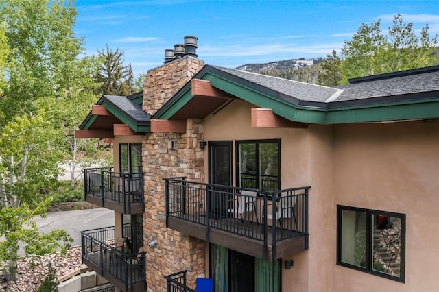 2883 Burgess Creek Rd Unit 302, Steamboat Springs, CO 80487 - rear view of property featuring a balcony, stucco siding, roof with shingles, and stone siding