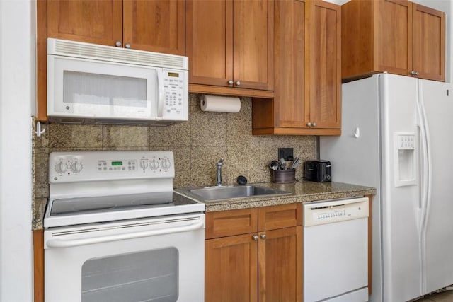kitchen featuring brown cabinets, tasteful backsplash, a sink, and white appliances
