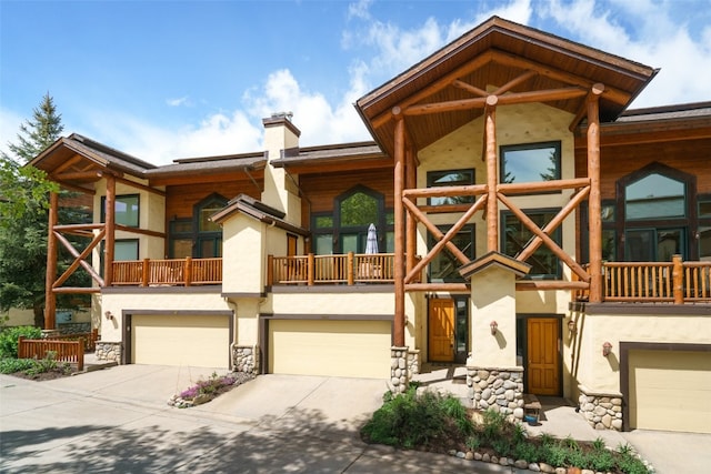 2685 Timber Ct Unit 2, Steamboat Springs, CO 80487 - view of front facade with a chimney, driveway, stone siding, a garage, and stucco siding