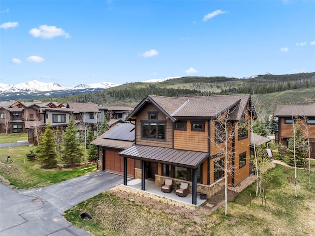 77 Red Quill Ln, Breckenridge, CO 80424 - view of front facade with a standing seam roof, stone siding, a mountain view, driveway, and metal roof