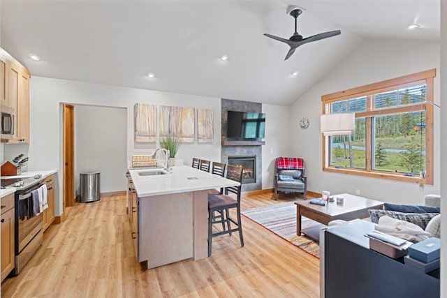 kitchen featuring a breakfast bar, stainless steel appliances, sink, a center island with sink, and a fireplace