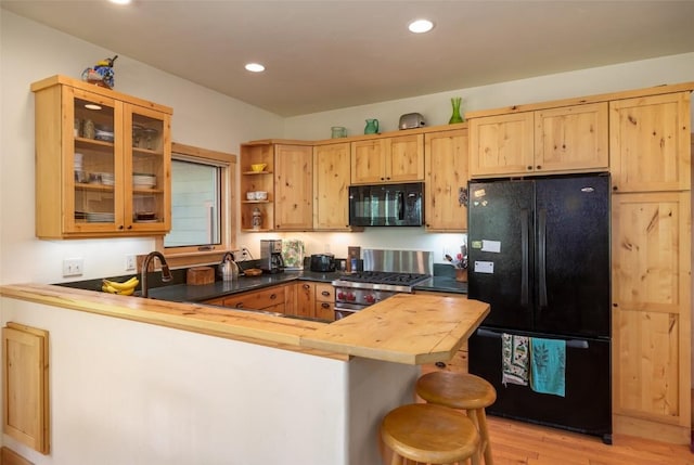 31020 Fallen Falcon Trl, Oak Creek, CO 80467 - kitchen featuring black appliances, a peninsula, butcher block counters, light wood finished floors, and glass insert cabinets