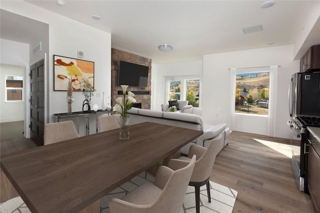 1030 Blue River Pkwy Unit A-302, Silverthorne, CO 80498 - dining room featuring baseboards, wood finished floors, visible vents, and a large fireplace