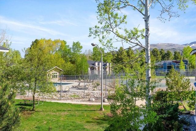view of home's community with a pool, a patio, and a mountain view