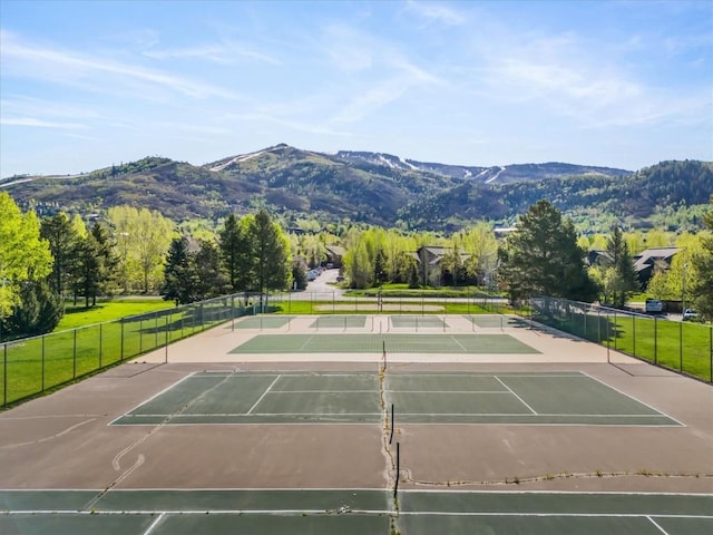 view of tennis court with fence, a mountain view, and community basketball court