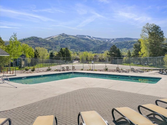 community pool featuring a mountain view, a patio area, and fence