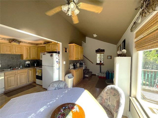 kitchen with backsplash, vaulted ceiling, a sink, freestanding refrigerator, and electric range