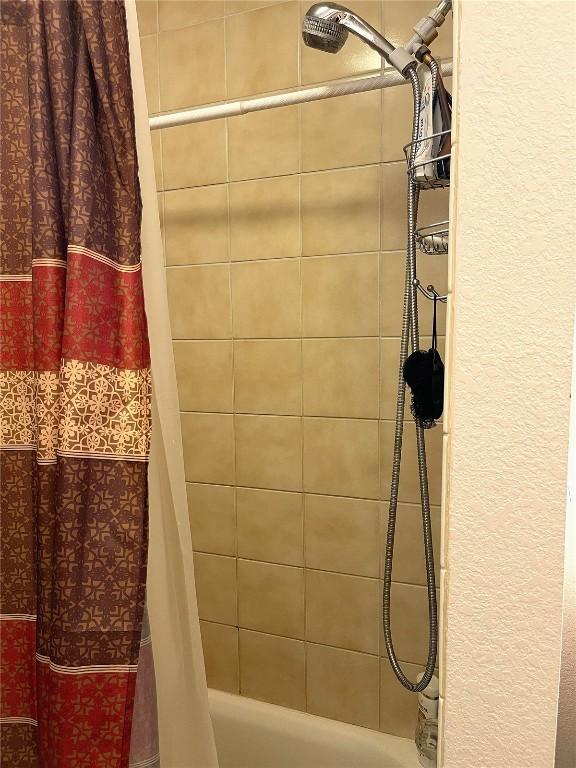full bathroom with shower / tub combo and a textured wall