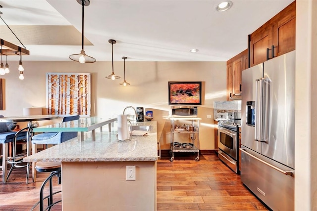 kitchen featuring light wood-type flooring, appliances with stainless steel finishes, a breakfast bar area, and a sink