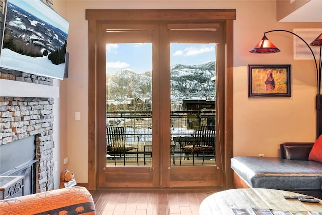 entryway with a mountain view, a stone fireplace, and wood finished floors