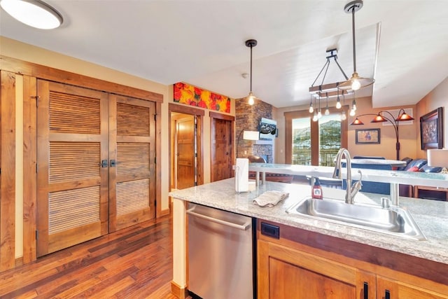 kitchen featuring wood finished floors, a sink, open floor plan, dishwasher, and pendant lighting
