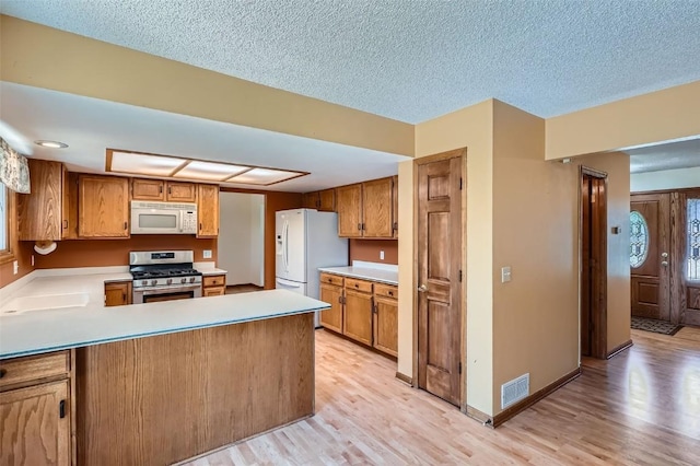 20596 E Shefield Ct, Parker, CO 80138 - kitchen featuring white appliances, light wood-style flooring, light countertops, a peninsula, and a textured ceiling