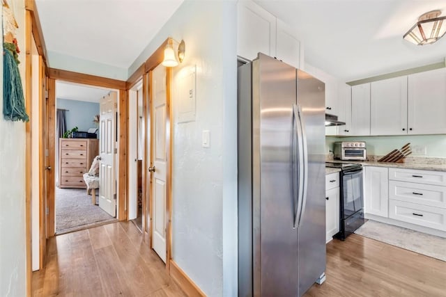 23800 County Road 16 Unit 204, Oak Creek, CO 80467 - kitchen with freestanding refrigerator, black range with electric stovetop, light wood finished floors, white cabinetry, and light stone countertops
