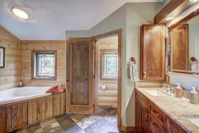 full bathroom featuring a garden tub, a sink, double vanity, lofted ceiling, and stone finish floor