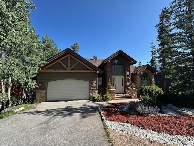 368 Black Hawk Cir, Silverthorne, CO 80498 - view of front of house with stone siding, asphalt driveway, an attached garage, and a chimney
