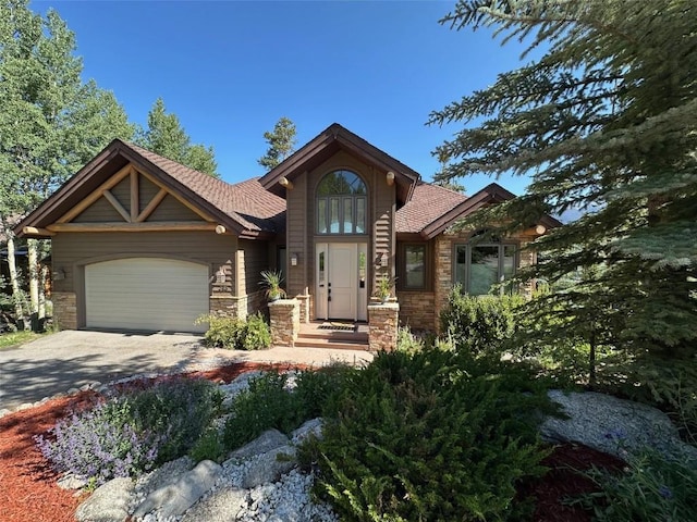 368 Black Hawk Cir, Silverthorne, CO 80498 - view of front of house with a garage, stone siding, driveway, and roof with shingles