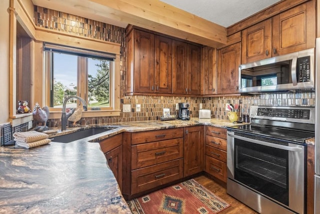 1720 Ranch Rd Unit 301, Steamboat Springs, CO 80487 - kitchen featuring stainless steel appliances, a sink, tasteful backsplash, and brown cabinetry
