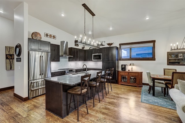 53 Hargrove Way, Silverthorne, CO 80498 - kitchen with stainless steel appliances, wall chimney exhaust hood, a sink, a kitchen breakfast bar, and a chandelier