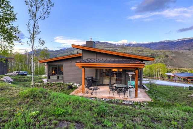 53 Hargrove Way, Silverthorne, CO 80498 - back of property with a standing seam roof, a mountain view, a chimney, a patio area, and metal roof