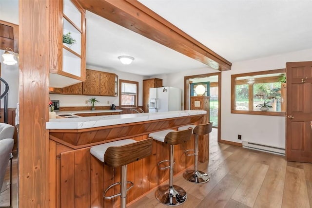 211 W Oak St, Oak Creek, CO 80467 - kitchen with baseboard heating, white fridge with ice dispenser, brown cabinetry, light wood-style floors, and light countertops