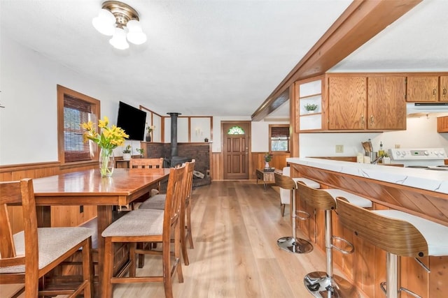 211 W Oak St, Oak Creek, CO 80467 - dining space with wainscoting, a wood stove, and light wood-style flooring