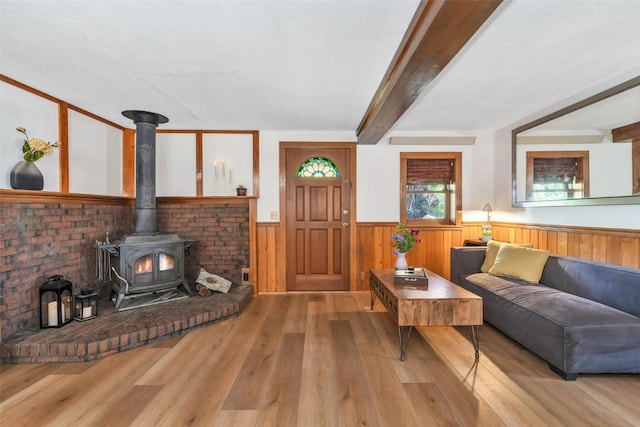 211 W Oak St, Oak Creek, CO 80467 - living area featuring a wood stove, wainscoting, wood finished floors, and beamed ceiling