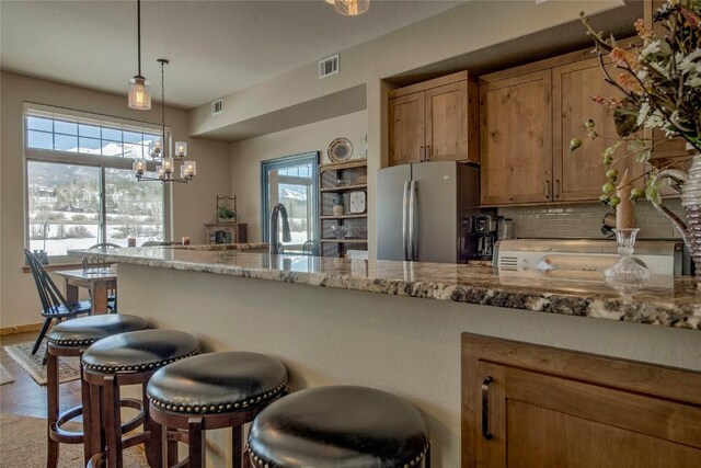 131 Allegra Ln Unit 131, Silverthorne, CO 80498 - kitchen featuring freestanding refrigerator, a sink, tasteful backsplash, a kitchen bar, and brown cabinets