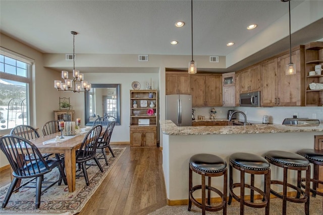 131 Allegra Ln Unit 131, Silverthorne, CO 80498 - kitchen with stainless steel appliances, brown cabinets, open shelves, a peninsula, and light stone countertops