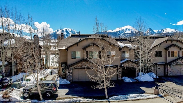 131 Allegra Ln Unit 131, Silverthorne, CO 80498 - view of front of home with an attached garage, driveway, stone siding, and a mountain view