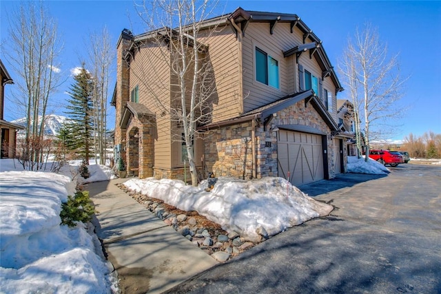 131 Allegra Ln Unit 131, Silverthorne, CO 80498 - snow covered property with stone siding, a garage, and driveway