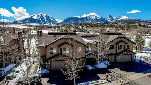 131 Allegra Ln Unit 131, Silverthorne, CO 80498 - view of front of house with an attached garage, a mountain view, driveway, and stone siding