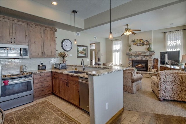 131 Allegra Ln Unit 131, Silverthorne, CO 80498 - kitchen with stainless steel appliances, open floor plan, a sink, a peninsula, and light stone counters