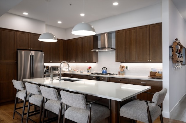 1460 Bangtail Way Unit 1B, Steamboat Springs, CO 80487 - kitchen featuring wall chimney range hood, a sink, decorative backsplash, a kitchen breakfast bar, and recessed lighting