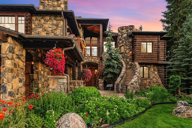 165 River Park Dr, Breckenridge, CO 80424 - back of property at dusk with a balcony, stone siding, a chimney, and a patio area