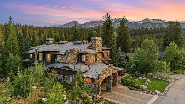 165 River Park Dr, Breckenridge, CO 80424 - view of front facade with a chimney, stone siding, a mountain view, and a wooded view
