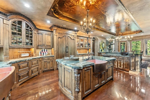 165 River Park Dr, Breckenridge, CO 80424 - kitchen featuring a chandelier, a raised ceiling, arched walkways, a kitchen island with sink, and dark wood-style flooring