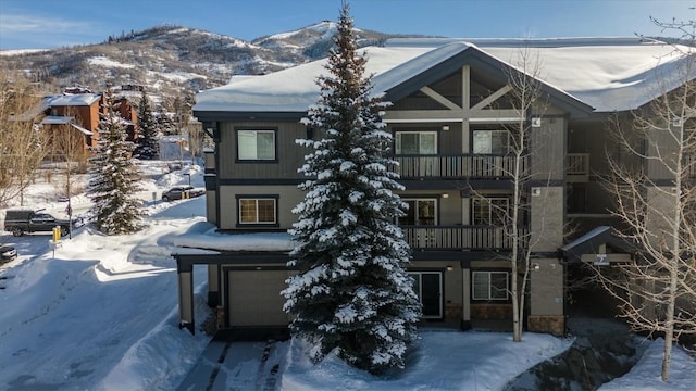 snow covered property with a garage and a mountain view