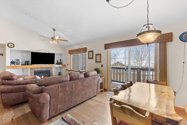 living room with ceiling fan, a fireplace, light hardwood / wood-style floors, and vaulted ceiling