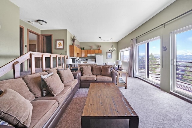 living area with light colored carpet, a wealth of natural light, a chandelier, and a textured ceiling