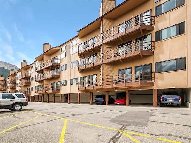 view of building exterior with covered and uncovered parking