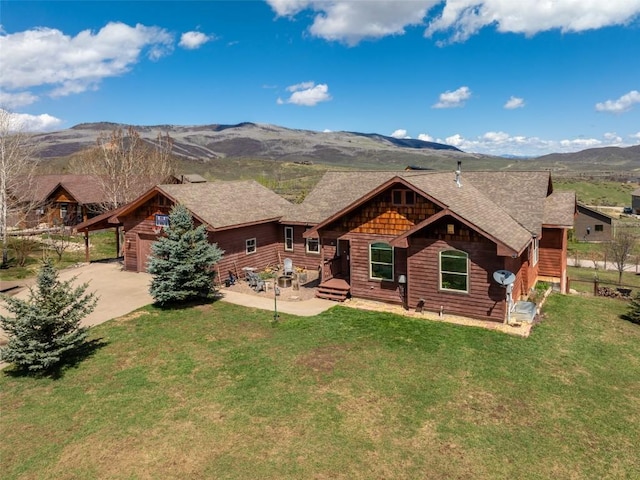 rear view of property featuring a lawn, concrete driveway, and a mountain view