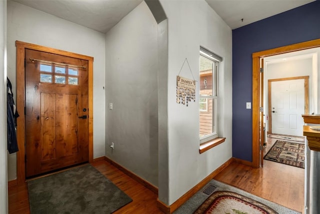 entryway with arched walkways, plenty of natural light, baseboards, and wood finished floors