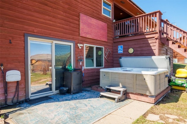 view of patio with a hot tub and stairway