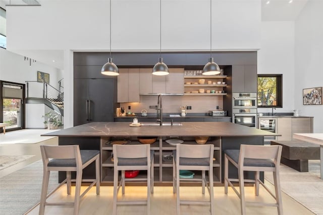 582 Laurel St, Steamboat Springs, CO 80487 - bar area with stainless steel double oven, a sink, a towering ceiling, and decorative light fixtures