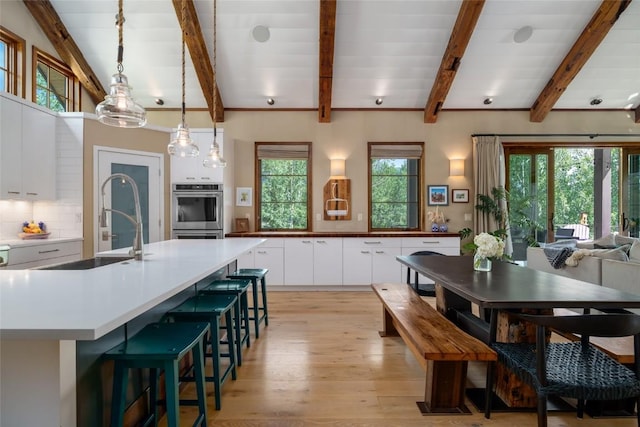 1511 Harwig Cir, Steamboat Springs, CO 80487 - kitchen with stainless steel double oven, a sink, light wood finished floors, white cabinetry, and backsplash