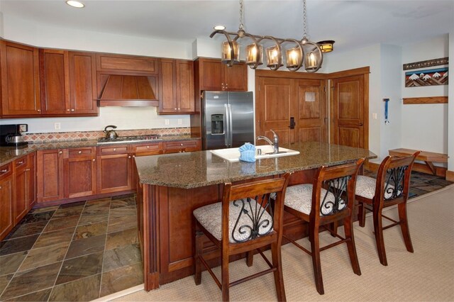 280 Trailhead Dr Unit 3037, Keystone, CO 80435 - kitchen featuring brown cabinets, a breakfast bar, premium range hood, a center island with sink, and appliances with stainless steel finishes