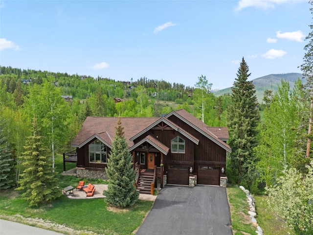 736 Wild Rose Rd, Silverthorne, CO 80498 - chalet / cabin with stone siding, driveway, a view of trees, a garage, and a mountain view