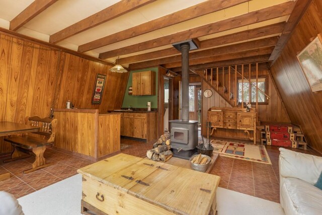 33 Sugar Loaf Ln, Jefferson, CO 80456 - living room featuring tile patterned flooring, wooden walls, a wood stove, beamed ceiling, and stairs