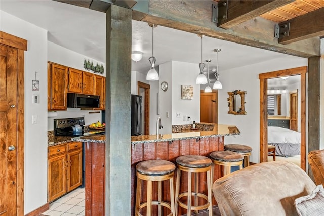 2700 Village Dr Unit C107, Steamboat Springs, CO 80487 - kitchen with black appliances, a kitchen bar, brown cabinets, dark stone countertops, and beam ceiling